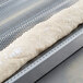 A long piece of baguette dough on a Chicago Metallic aluminum baguette pan.