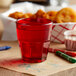 A red GET Bahama plastic tumbler filled with red liquid on a table with crayons and a basket of chicken nuggets.