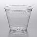 A Fabri-Kal Greenware clear plastic squat cup on a gray surface.