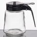 A Tablecraft modern glass syrup dispenser with a black ABS top and handle.