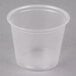 A clear plastic Dart souffle cup with a clear lid on a grey surface.