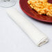 A white Hoffmaster FashnPoint linen-feel napkin on a table with a plate of macaroni and cheese.