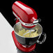 A white KitchenAid stand mixer mixing batter in a bowl with a white Flex Edge Flat Beater attachment.