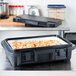 A black Cambro food pan carrier with food inside.