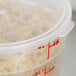 A Cambro translucent plastic food storage container with pasta inside on a counter.