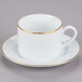 A white cup with a gold rim and a saucer.