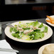 A plate of salad and chicken on a white Thunder Group Nustone melamine plate.