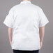 A man wearing a white Chef Revival short sleeve cook shirt with the back view visible.