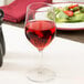 A Stolzle all-purpose wine glass filled with red wine on a table next to a salad plate.
