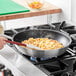 A person cooking food in a Choice aluminum non-stick frying pan on a stove.