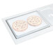 A Vollrath stainless steel sheet pan adapter plate on a counter with two pizzas on it.