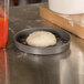A ball of dough in an American Metalcraft hard coat anodized aluminum pizza pan.