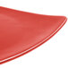 A close-up of a red CAC Festiware triangle flat plate with a curved edge.