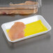 A white foam tray with a yellow absorbent pad holding a piece of meat over yellow liquid.