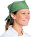 A smiling chef wearing a seafoam green chef bandana.