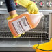A person in yellow gloves holding a yellow jug of Noble Chemical heavy duty degreaser.