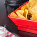 A red polyethylene square basket filled with chips on a table in a Mexican restaurant.