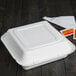 A white Bare by Solo sugarcane take-out container with sauces and napkins.