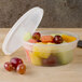 A Pactiv translucent plastic deli container filled with fruit on a table.