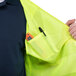 A man attaching a pocket to a Cordova Lime high visibility safety vest using a tool.