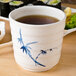 A Thunder Group Blue Bamboo melamine tea cup filled with tea on a table.