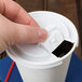 A hand opening a coffee cup with a white Solo plastic lid.