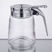 A clear glass Tablecraft syrup dispenser with a chrome metal handle.