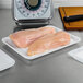 Raw chicken breasts on a white foam meat tray on a cutting board
