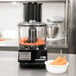 A Waring food processor with a bowl of carrots in it.