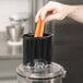 A person using a Waring food processor to slice carrots.