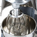 A Vollrath wire whisk inside a mixer with a metal bowl.