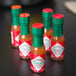 A group of TABASCO® Original Hot Sauce mini bottles with red and green caps.