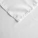 A close up of a white Intedge square cloth table cover with a hemmed corner.