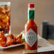A bottle of TABASCO® Original Hot Sauce on a table with chicken wings.