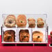 A Cal-Mil acrylic display case with different types of bread on a counter.