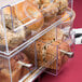 A Cal-Mil clear acrylic container with bread, bagels, and muffins.