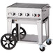 A Crown Verity stainless steel portable outdoor BBQ grill on a cart with wheels.