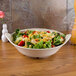 A GET Olympia melamine bowl of salad with tomatoes and cheese on a table.