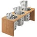 A Cal-Mil bamboo flatware holder with three metal cylinders holding silverware.