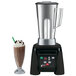 A Waring commercial blender with a glass of chocolate milkshake.