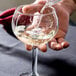 A person pouring wine into a Libbey round wine glass.
