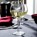 A Libbey round wine glass filled with white wine on a table