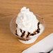 A WNA Comet Classic Sundae Cup filled with ice cream and chocolate syrup with a spoon.