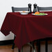 A table with a burgundy Intedge tablecloth and a plate of food.