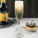 A Libbey Domaine flute of champagne with a chocolate cake on a table.