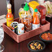 A HS Inc. Paprika Polyethylene condiment organizer on a table with bowls of salsa and condiments.