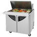 A Turbo Air sandwich prep table with a stainless steel top and wheels.