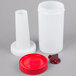 A white plastic Carlisle Store 'N Pour container with a red spout and cap.