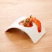 A shrimp in a rectangular white porcelain bowl with a sauce and a sprig of thyme.
