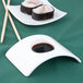 A rectangular white porcelain bowl with sushi and soy sauce on it.